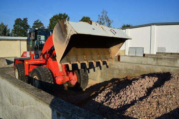 Ein Schaufel-Bagger vor einem Haufen Baustoff